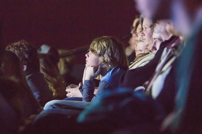 People in a cinema with a kid leaning forward in his seat