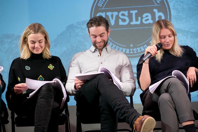 A man and two woman sitting down reading scripts