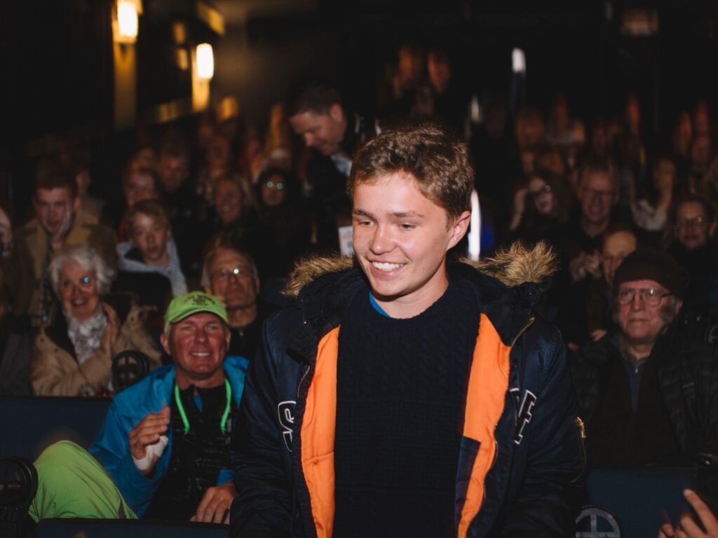 A young man walking up to stage infront of audience