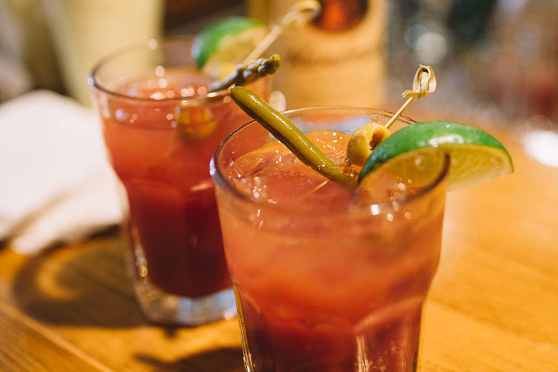 Two bloody mary cocktails on a table with a lime garnish